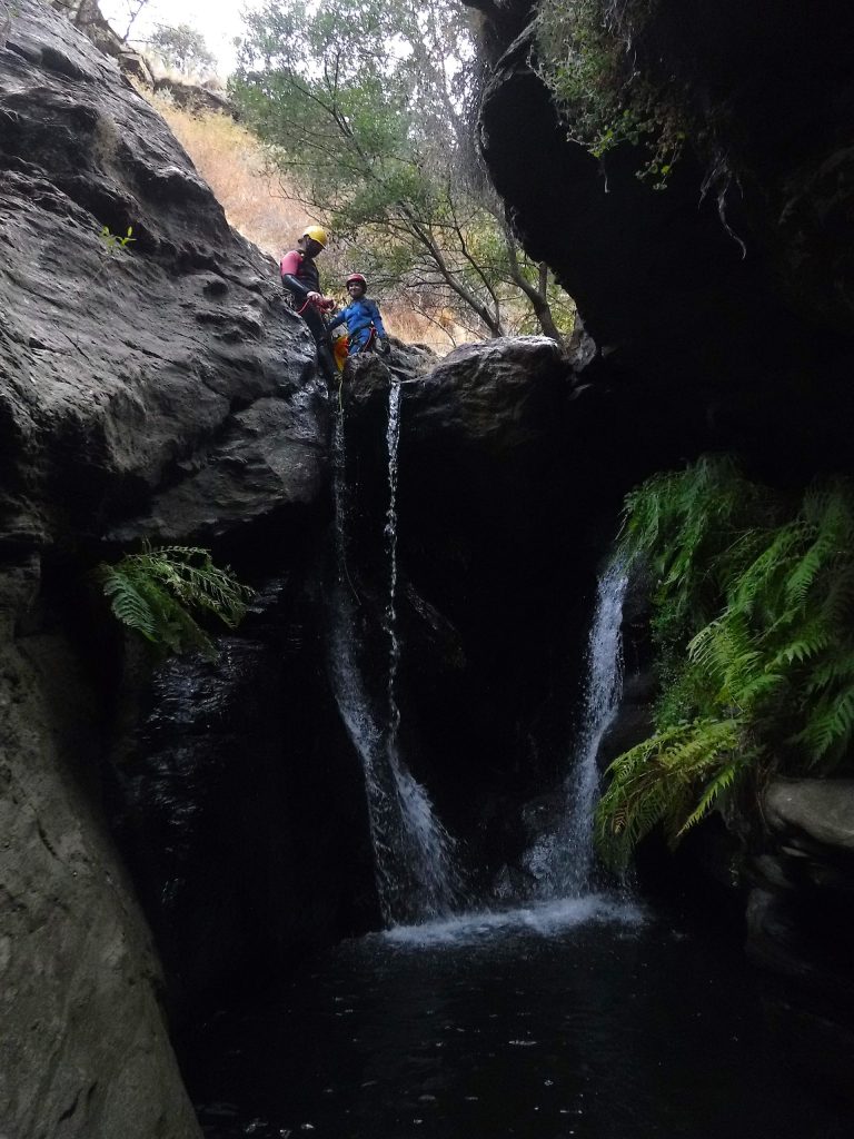 Un monitor de barrancos con una clienta bajando una cascada